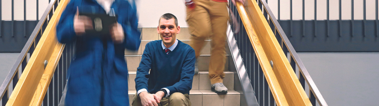 Principal sitting on stairs smiling