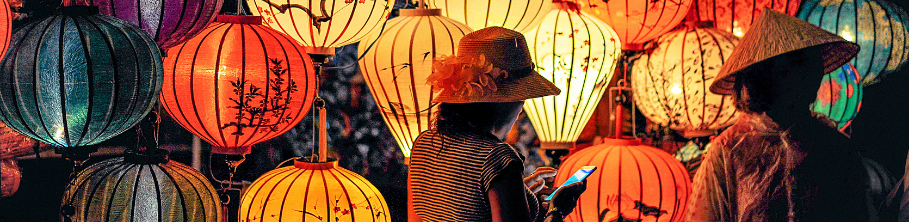 Women standing in front of Chinese lanterns; nighttime scene.