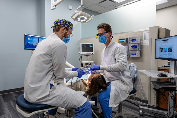 Two dental students working on a patient