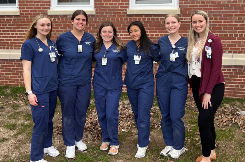 Five girls pose together in nursing scrubs.