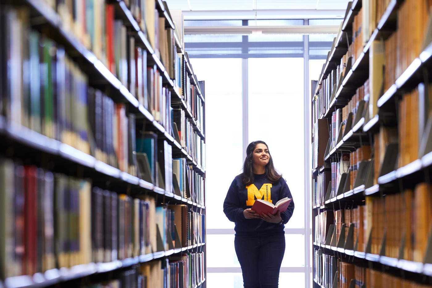 students walks in library isle observes books