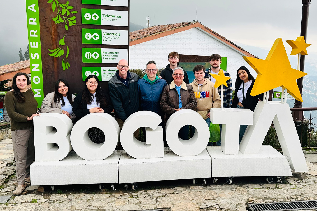 students and faculty pose by Bogota sign during international experience