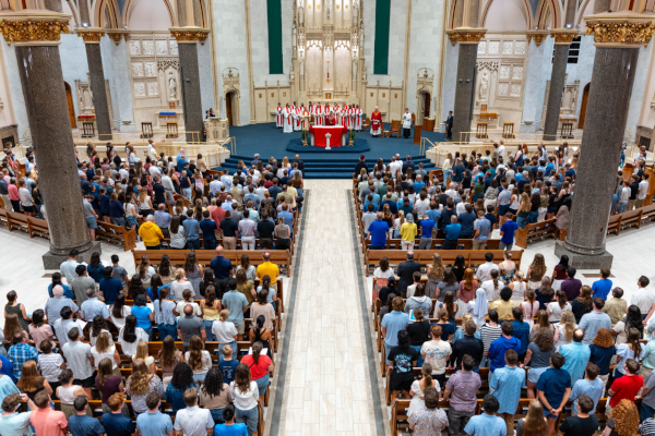 Families stand in the pews of the Church of the Gesu