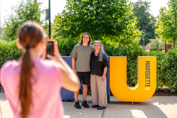 Student and parent stand in front of "MU" letters.