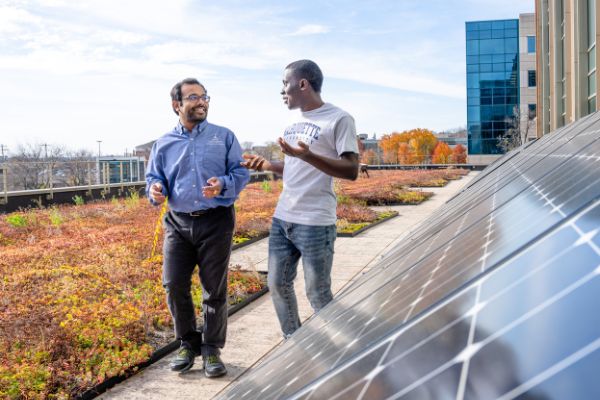 student and faculty speaking on green roof