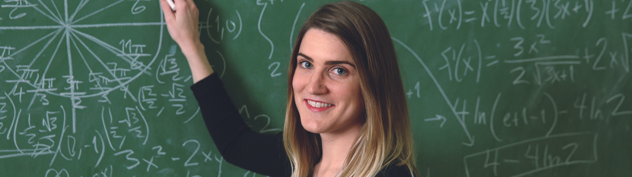 STEM Teacher smiling at a chalkboard with math equations in the background