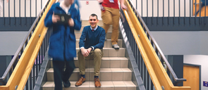 Graduate of the M.Ed in Educational Leadership program sitting on stairs