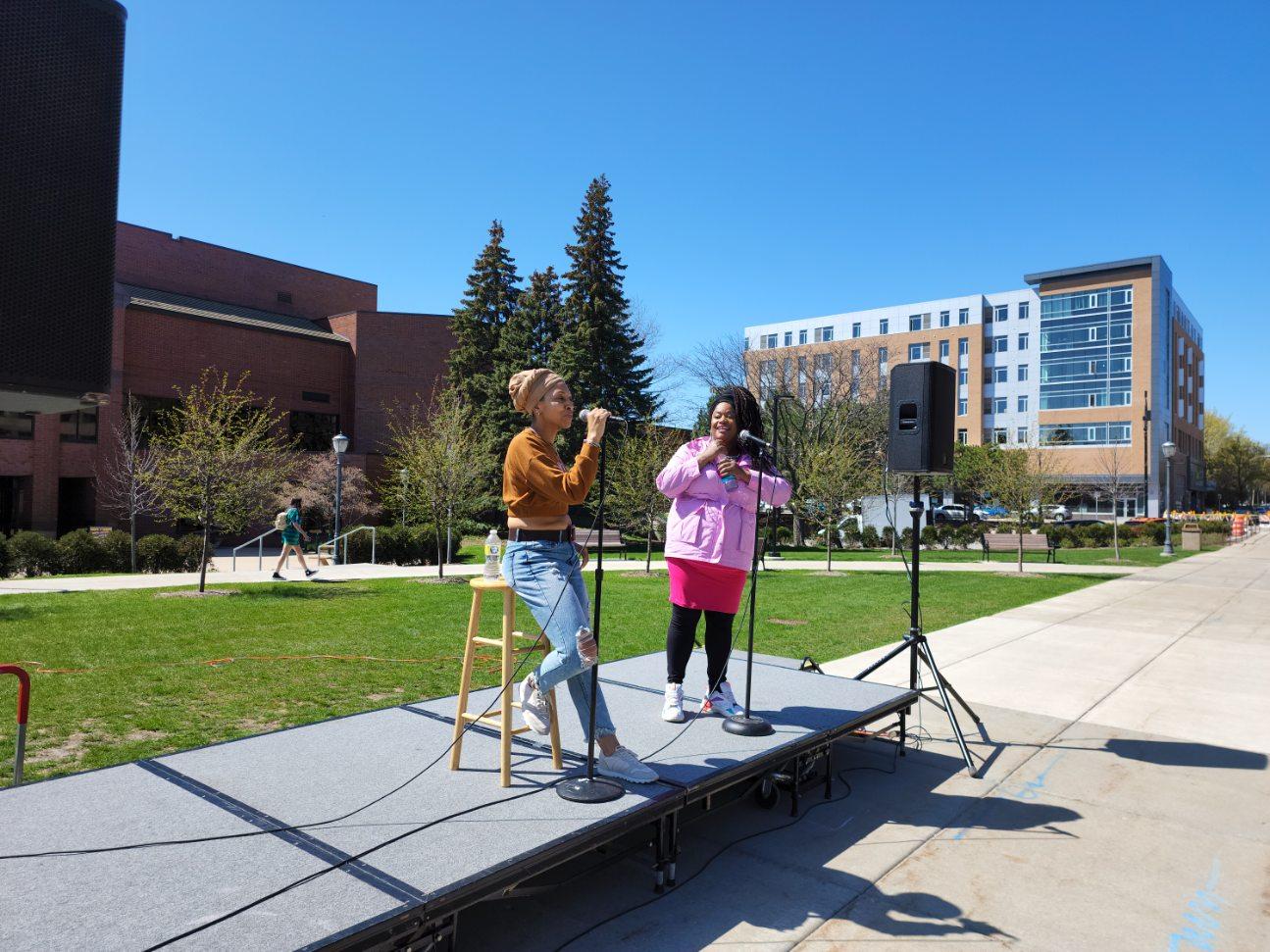 Two performers on a stage outside the MU AMU