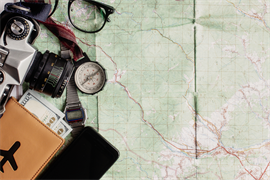 Assorted travel paraphernalia such as a travel map, compass, tickets, and glasses.