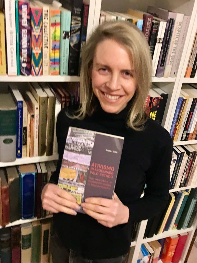 Jessica Rich holding her book in front of bookshelf