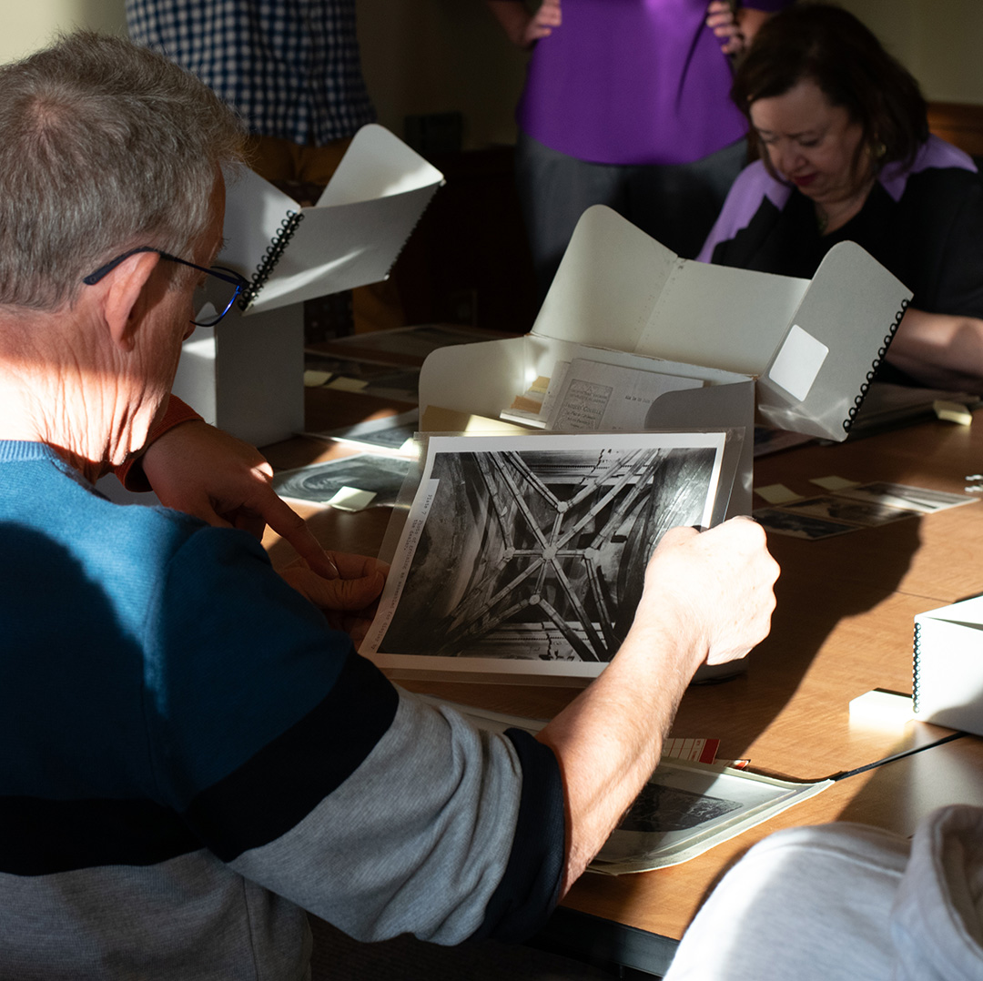 man seated at archivese table looking through photographs of joan of arc chapel