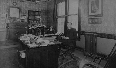 Monsignor William Henry Ketcham with his adopted son Tom (Choctaw), in his office at the Bureau of Catholic Indian Missions