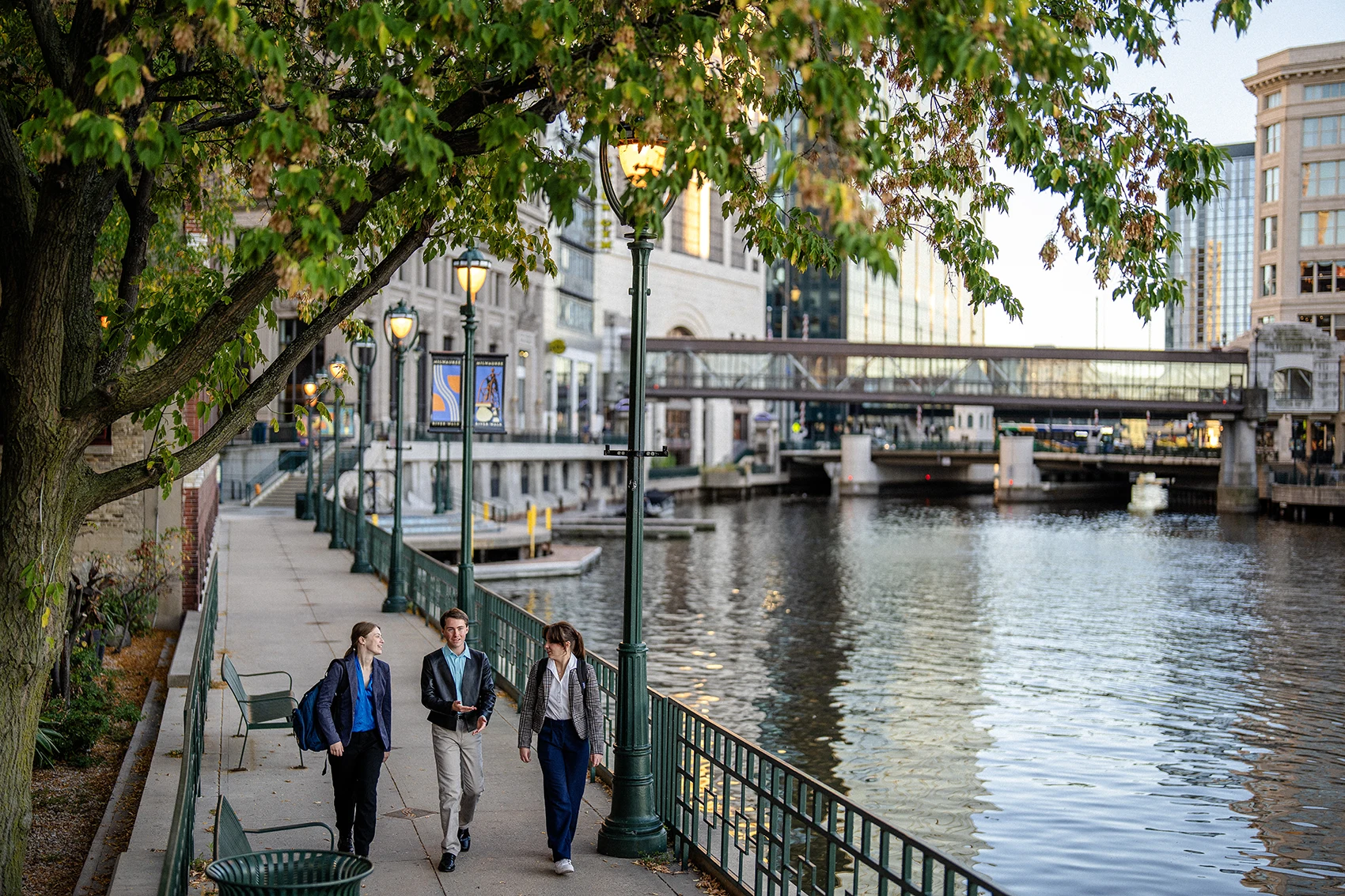 stuents walk next to the milwaukee river in downtown milwaukee