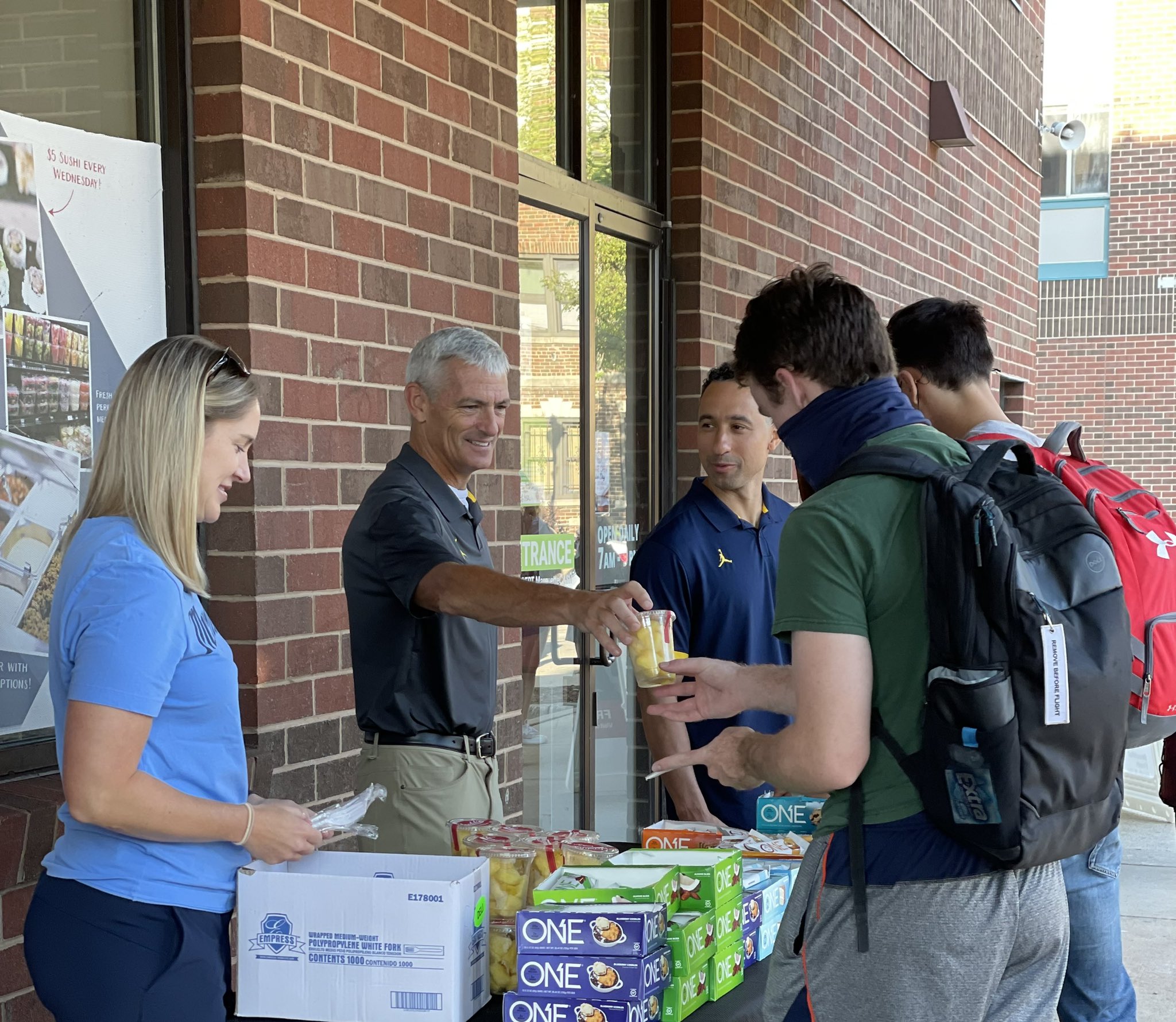 University president and basketball coaches handing out breakfast on first day of classes