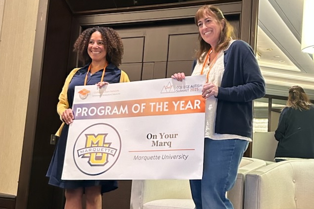 Emily Raclaw (left) holding a "Program of the Year" banner