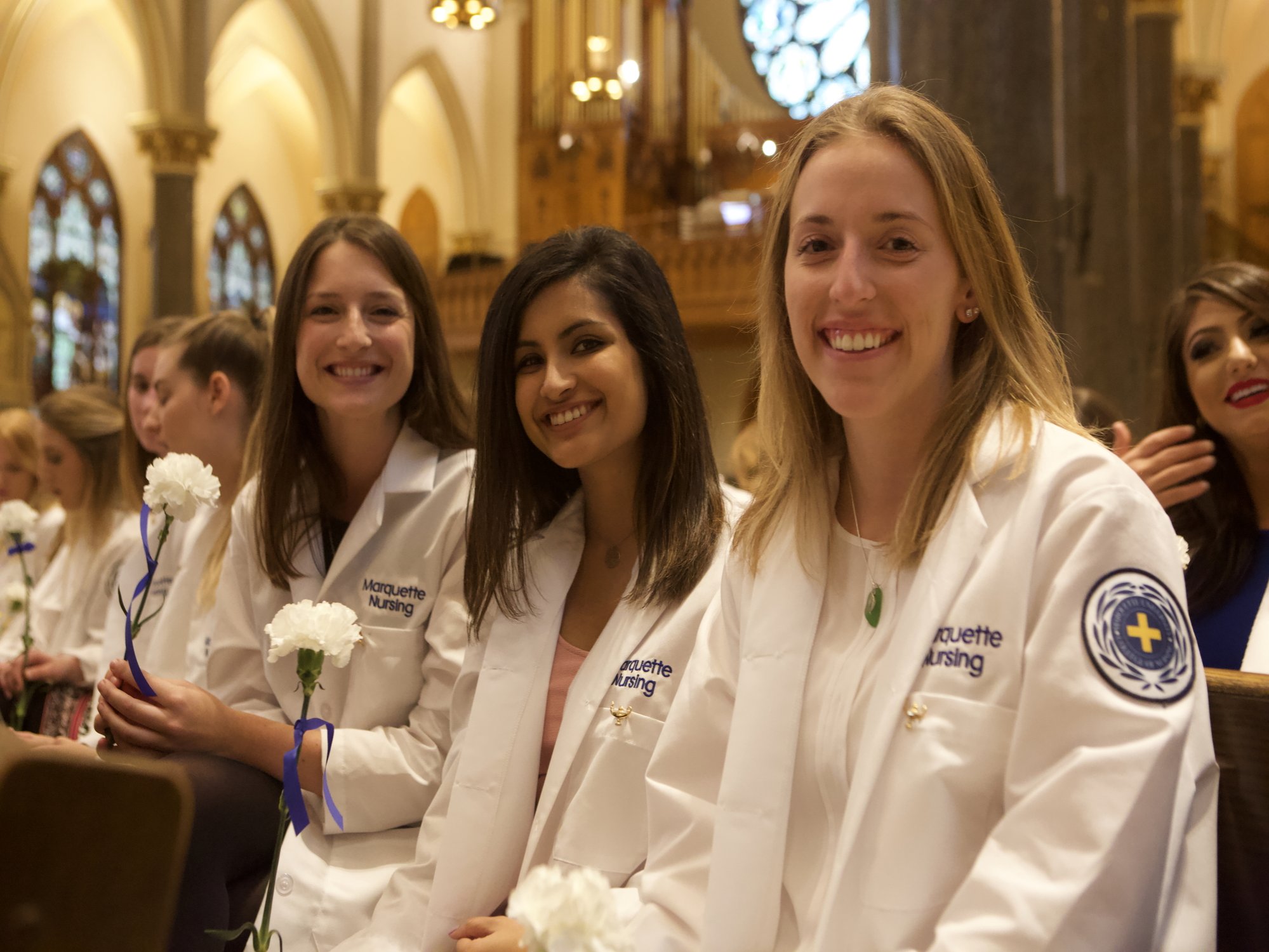 Three white coat nursing students smile