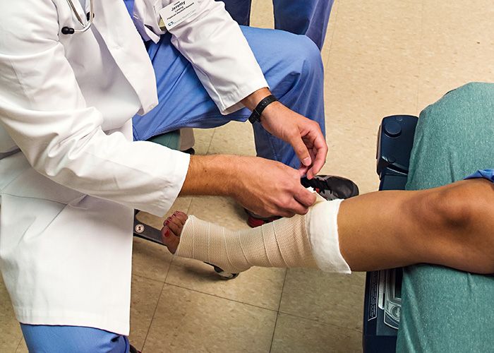 Physician assistant student bandages a patient's leg