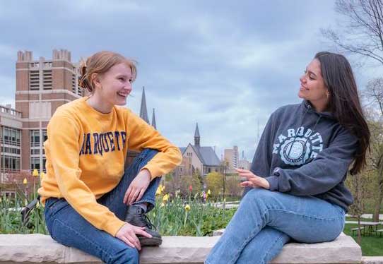 Students converse on campus wearing Marquette branded sweatshirts