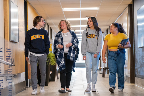 four students talk in the hallway