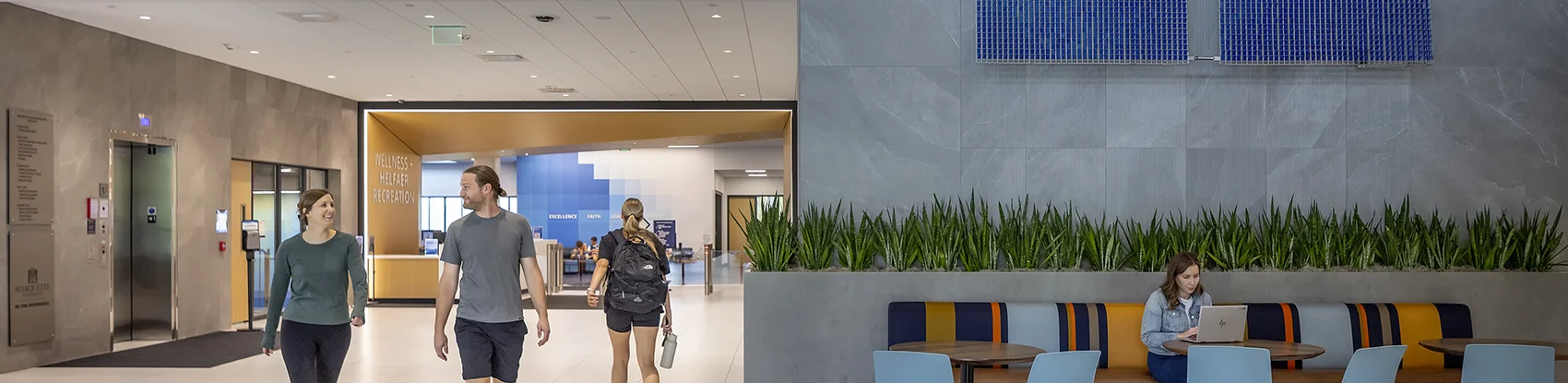 Man on a row machine with people standing near by. 