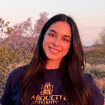 Ben sits on a step in a striped shirt, smiling. 